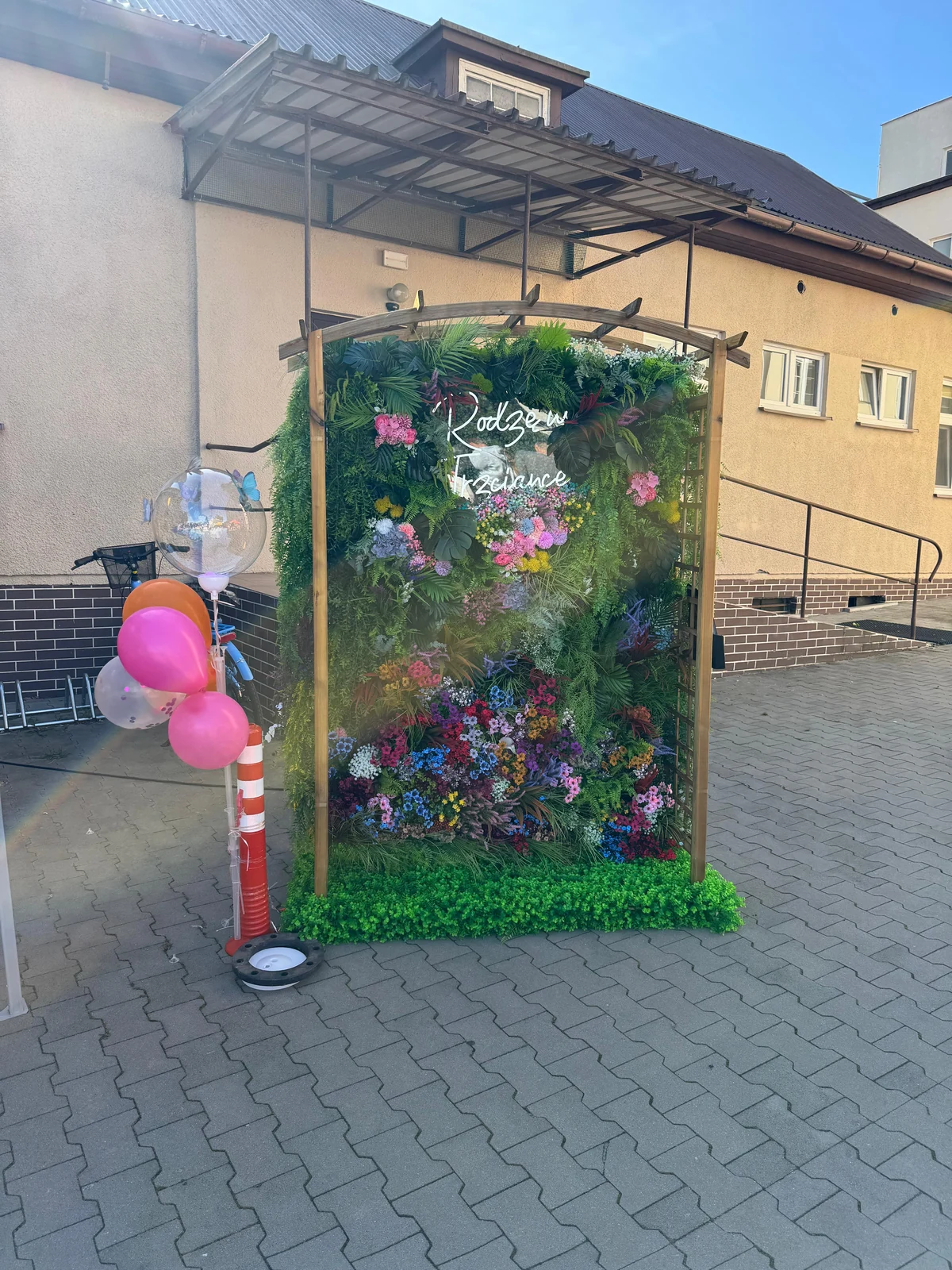 Cała fotościanka Green Thumbs z napisem Rodzę w Trzciance, ustawiona przed budynkiem szpitala podczas pikniku.